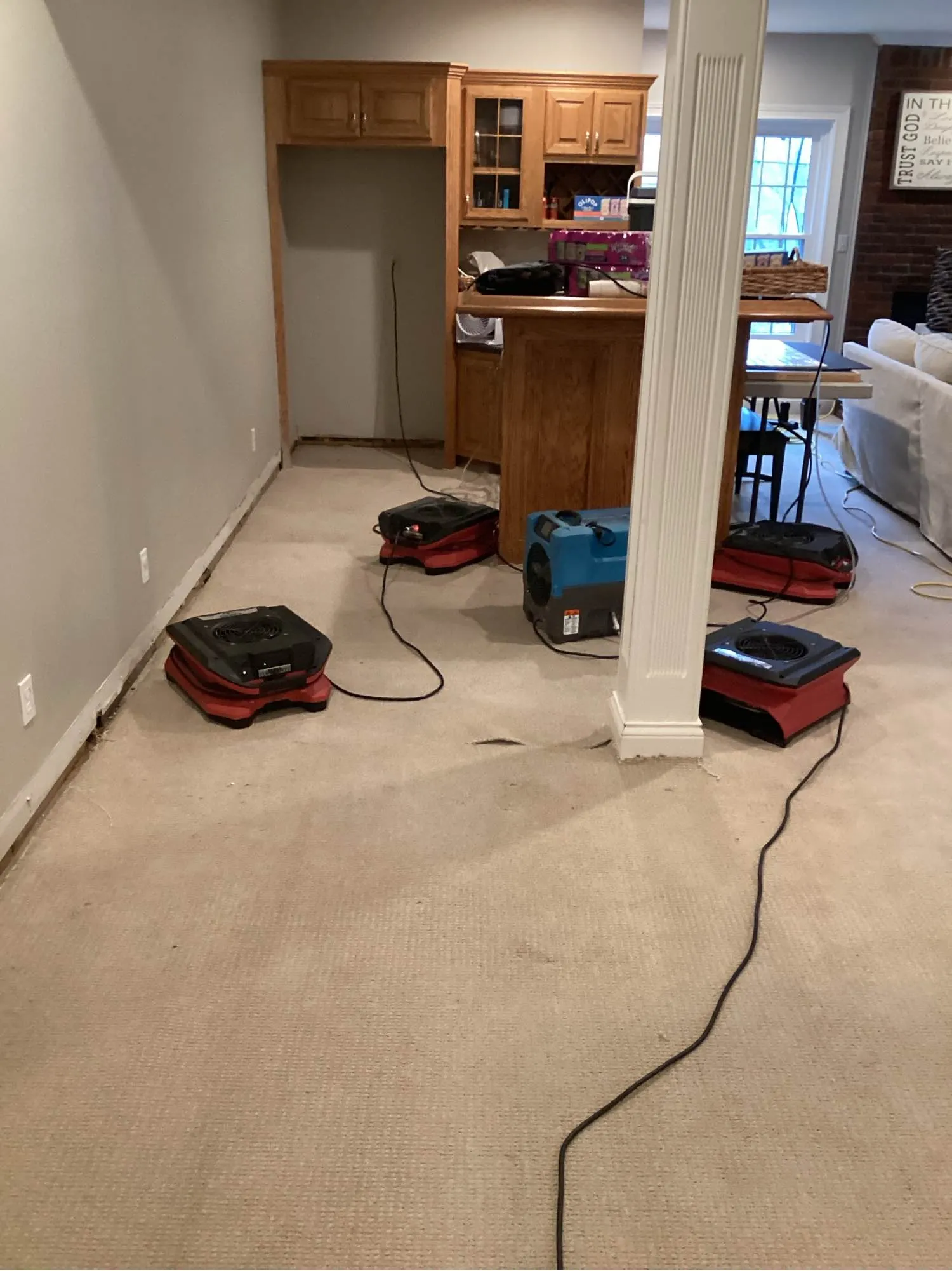 Air movers and a dehumidifier drying the carpet in a finished lower level after a basement flood