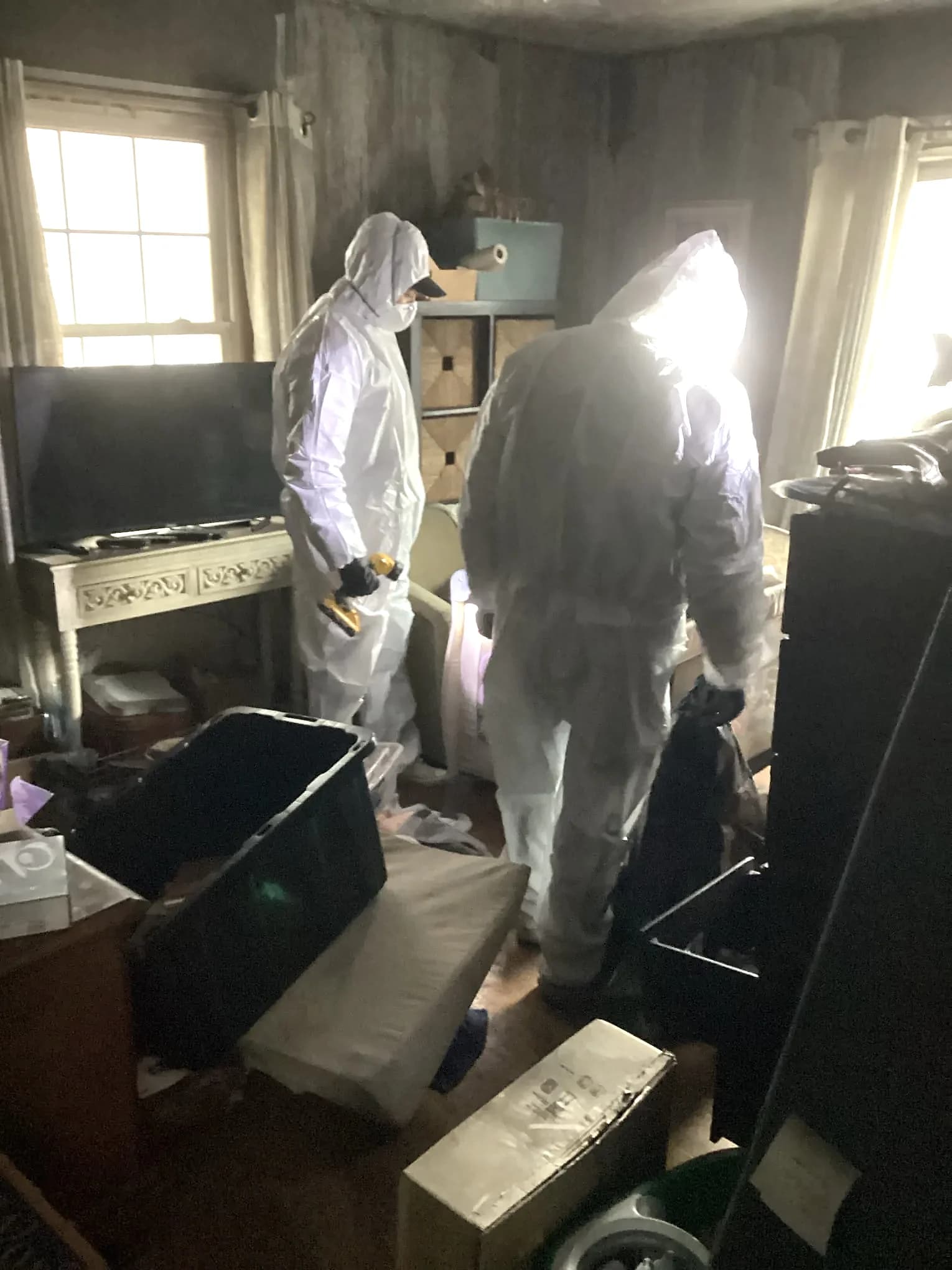 Two technicians in protective coveralls working inside a property during restoration
