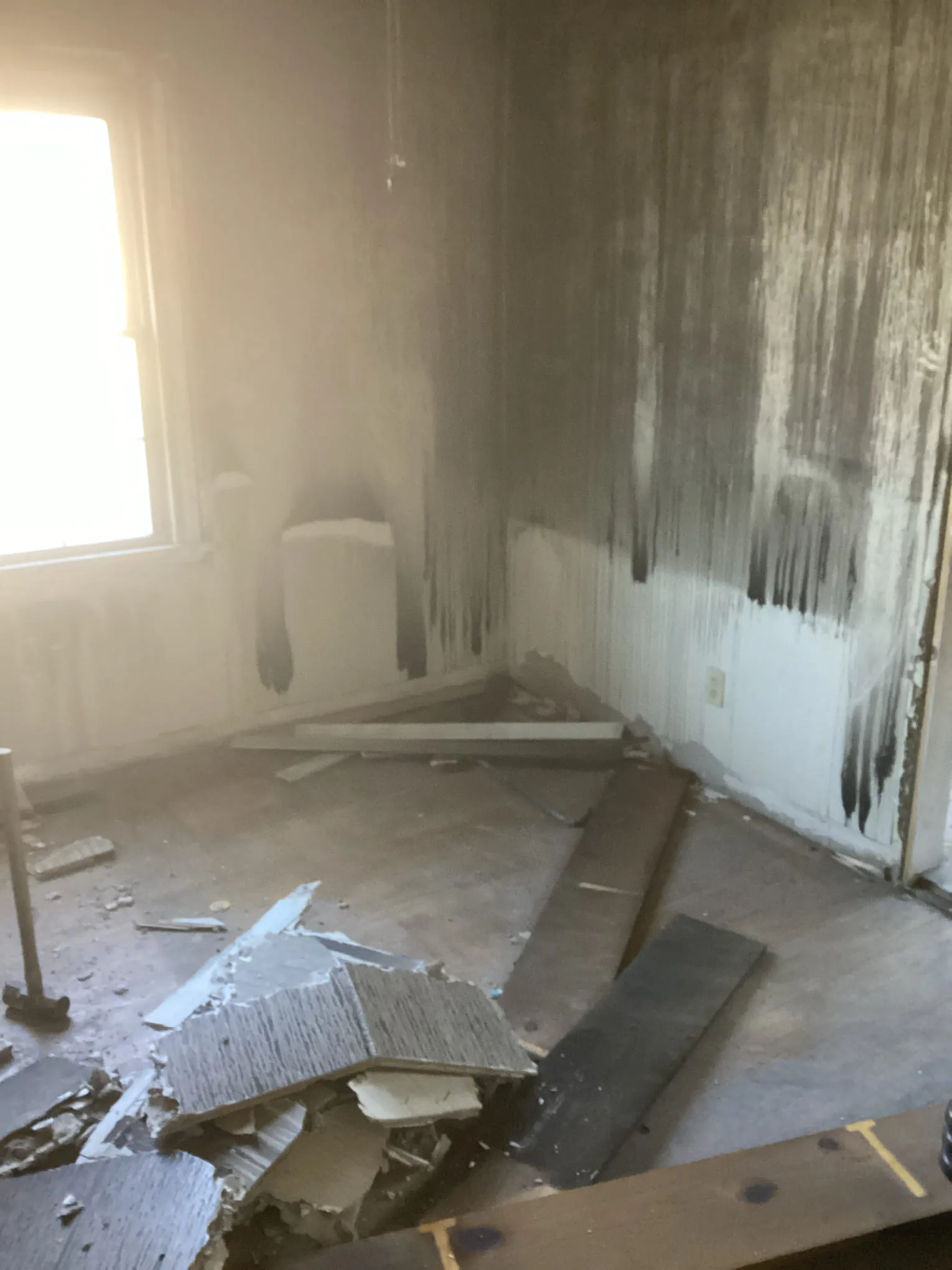 Fire-damaged interior room with charred walls and debris before restoration work begins