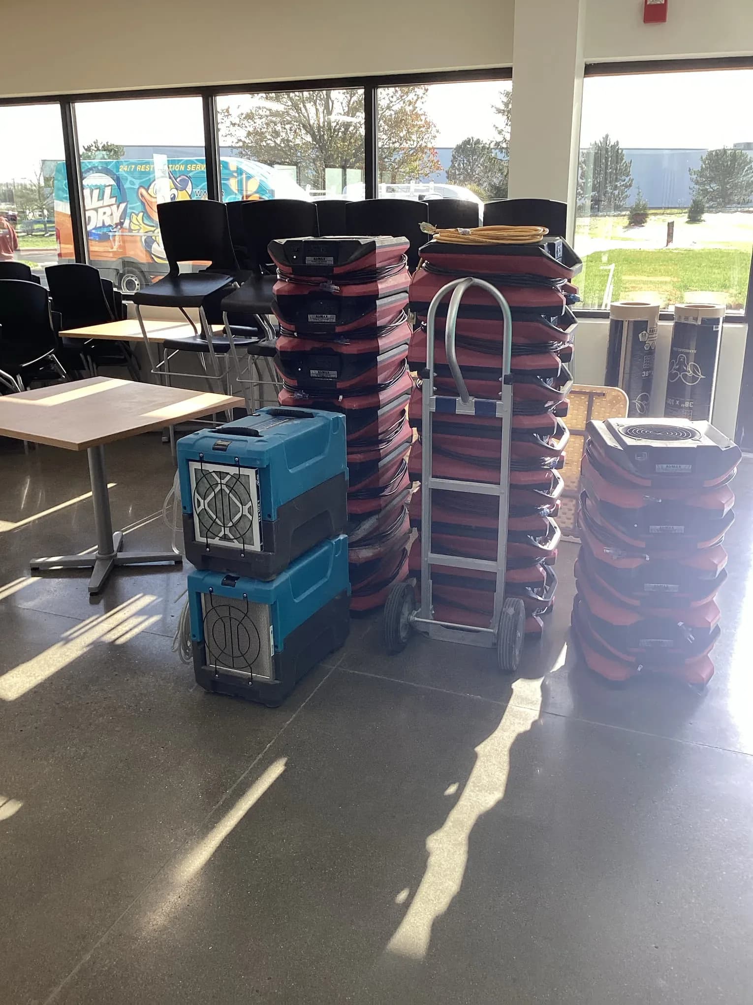 Commercial air movers and dehumidifiers staged in a glass-fronted lobby during a water damage job
