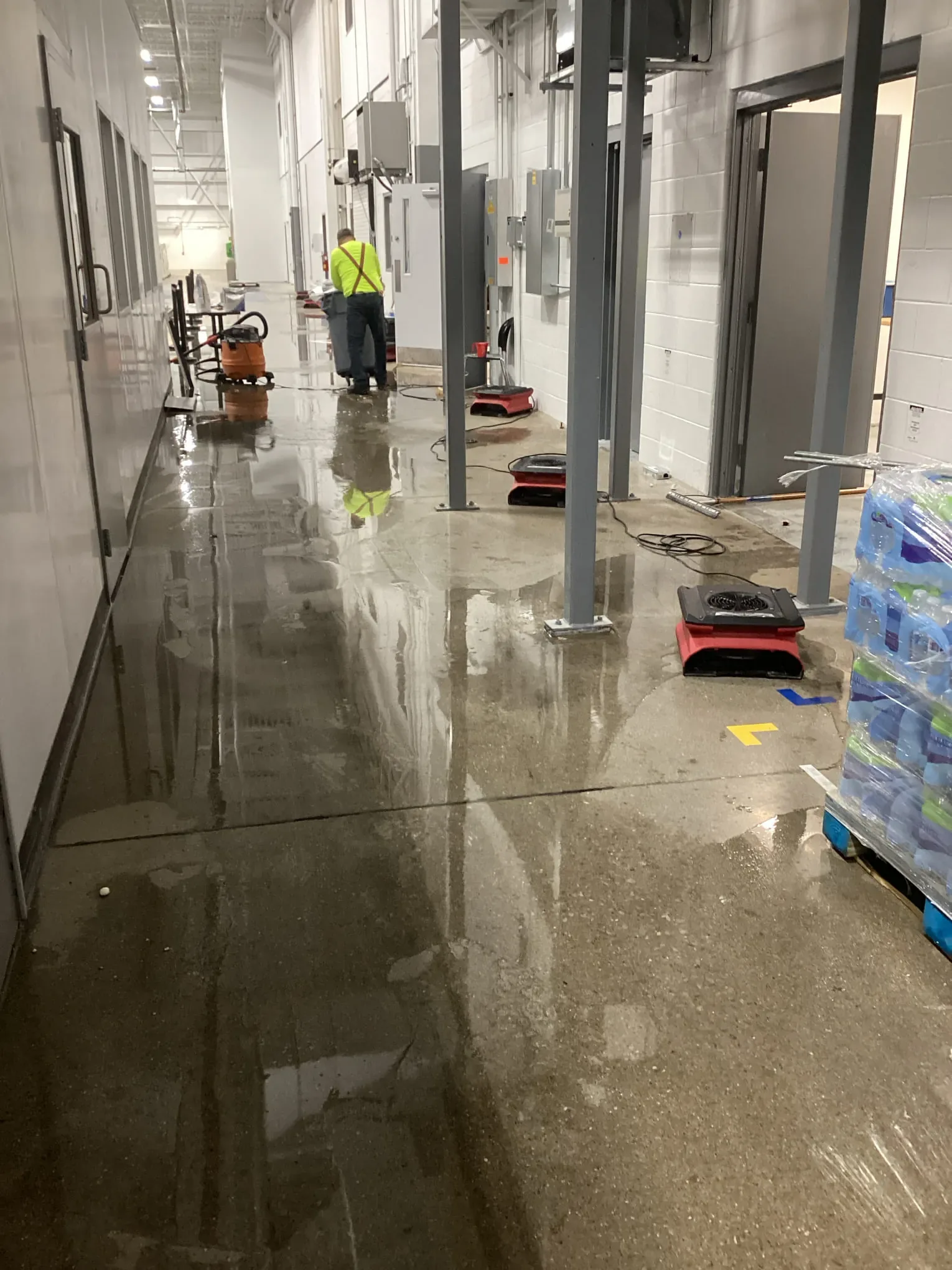 All Dry technician working along a flooded hallway with extraction and drying equipment at a Louisville property