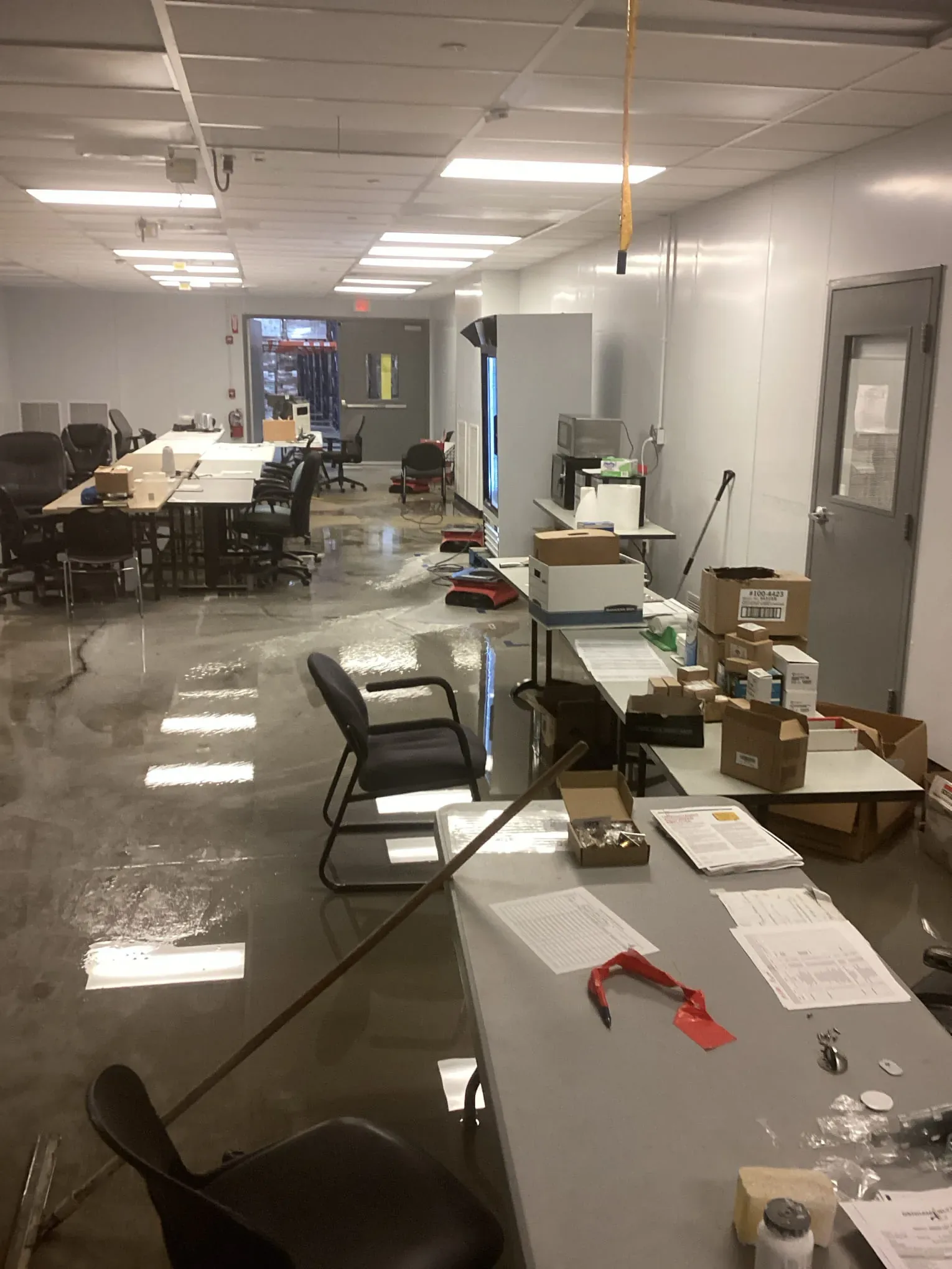 Open-plan office with standing water across the floor between desks after a water intrusion