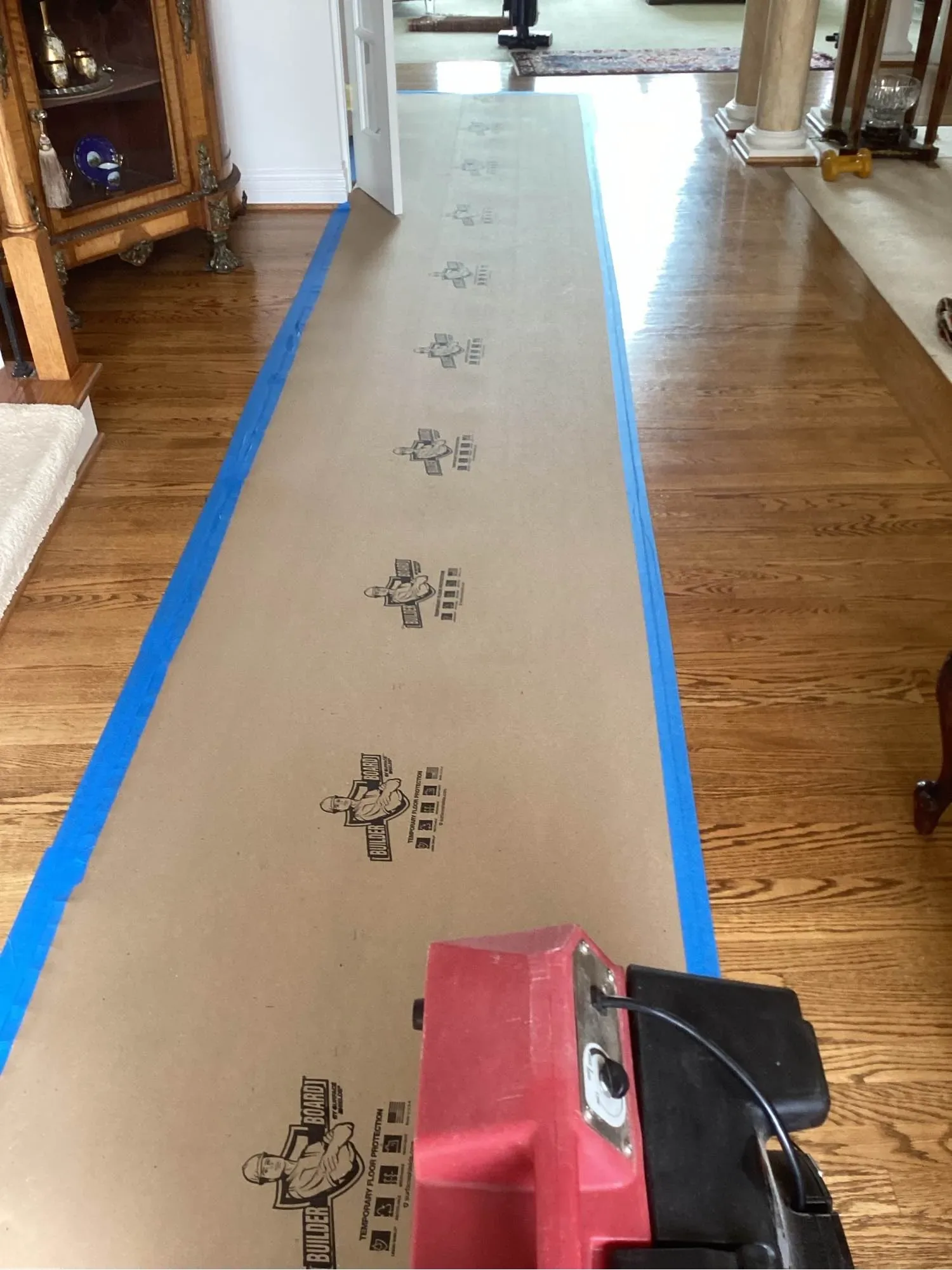 Protective covering taped down a hardwood hallway before extraction equipment is brought through