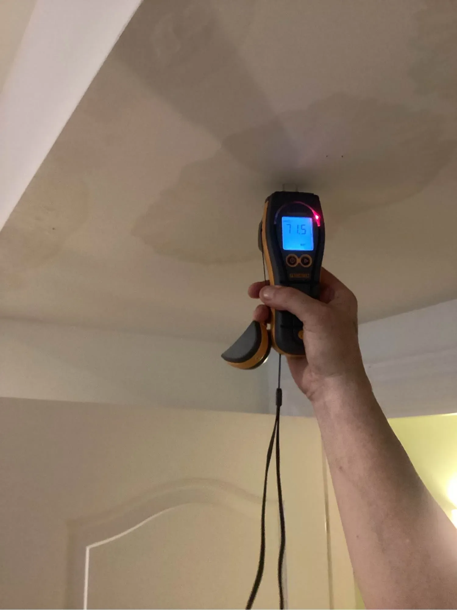 Moisture meter reading taken against a water-stained ceiling after storm water entered through the roof
