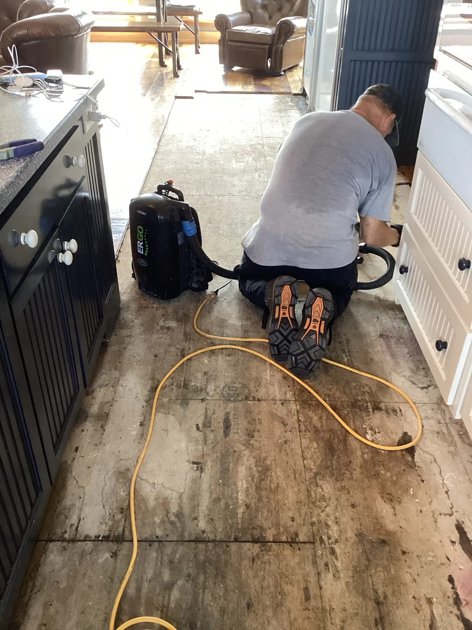 Technician extracting water from an exposed kitchen subfloor