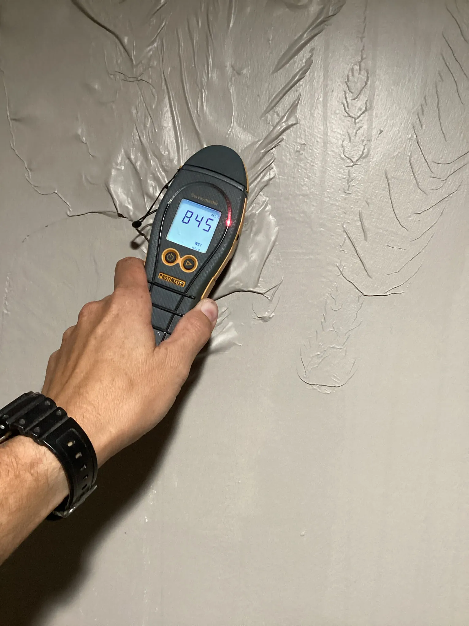 Technician taking a protimeter moisture reading on a wall during a Louisville water damage inspection