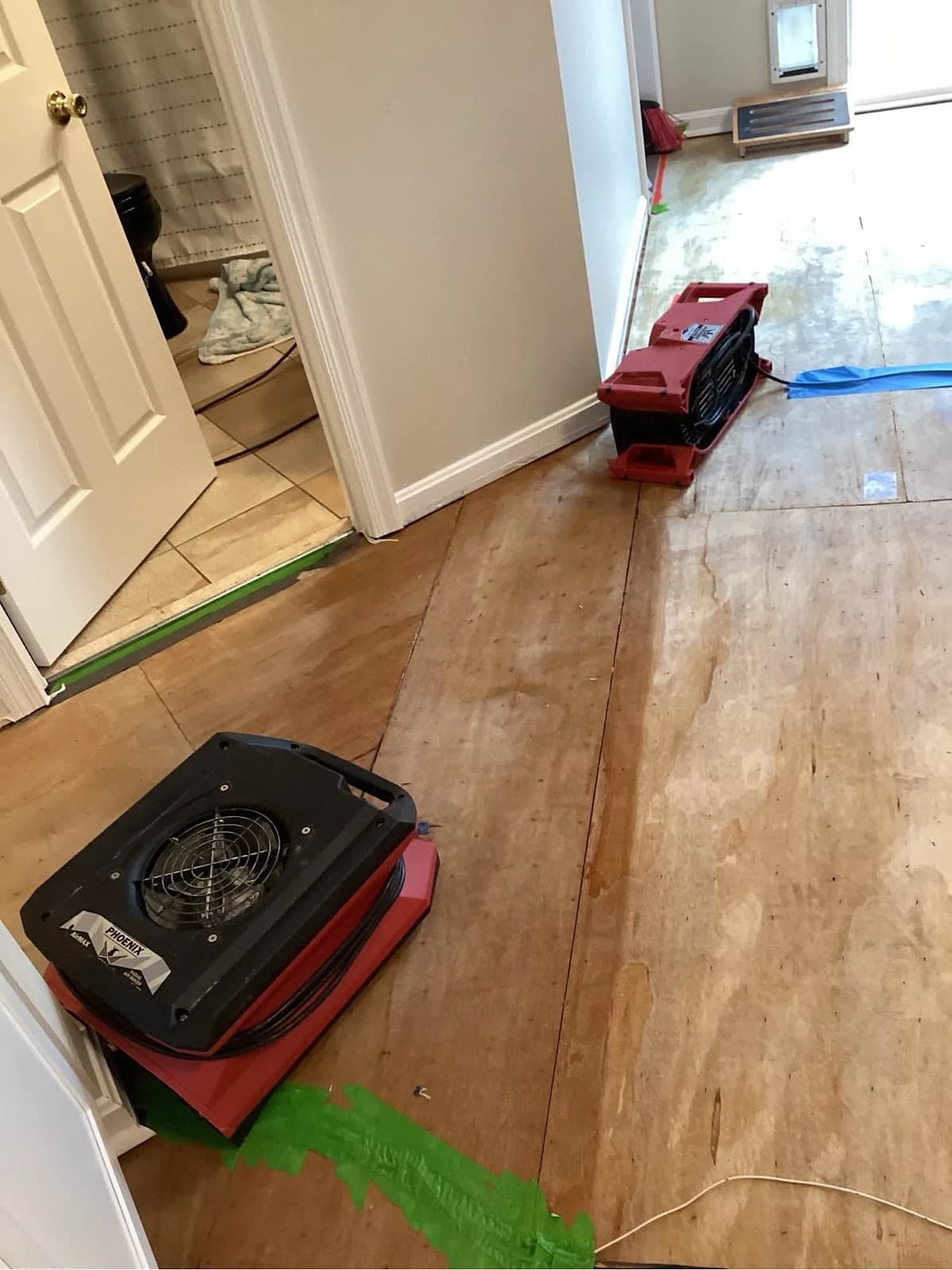 Air movers directed at an exposed subfloor to dry structural materials after water damage