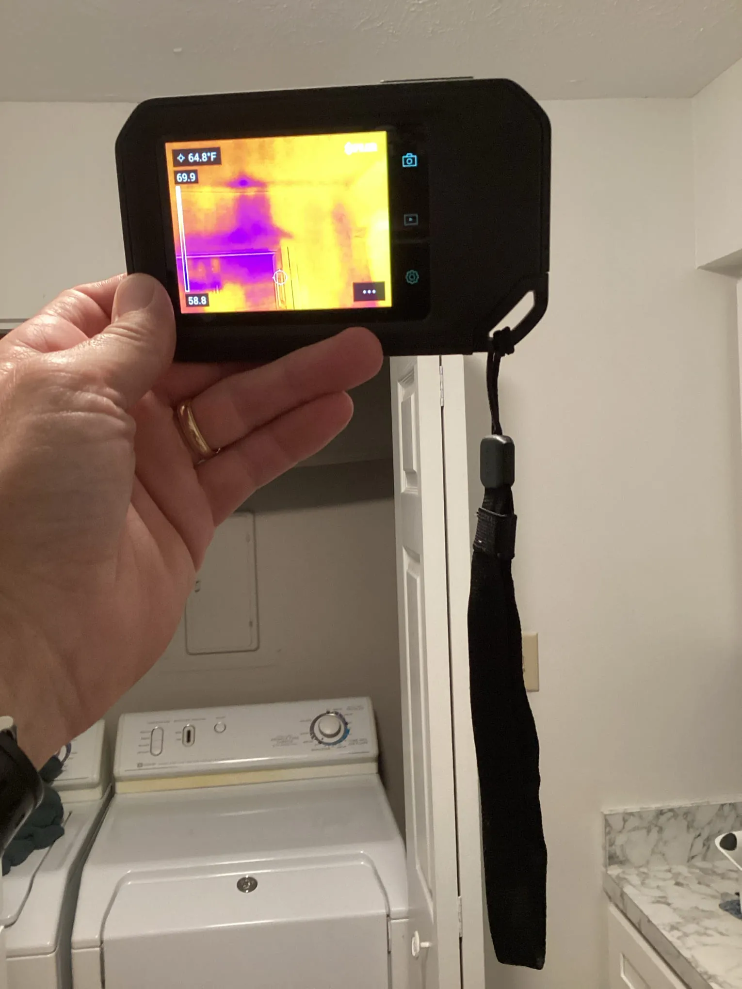 Technician using a thermal imaging camera to trace moisture near a door frame