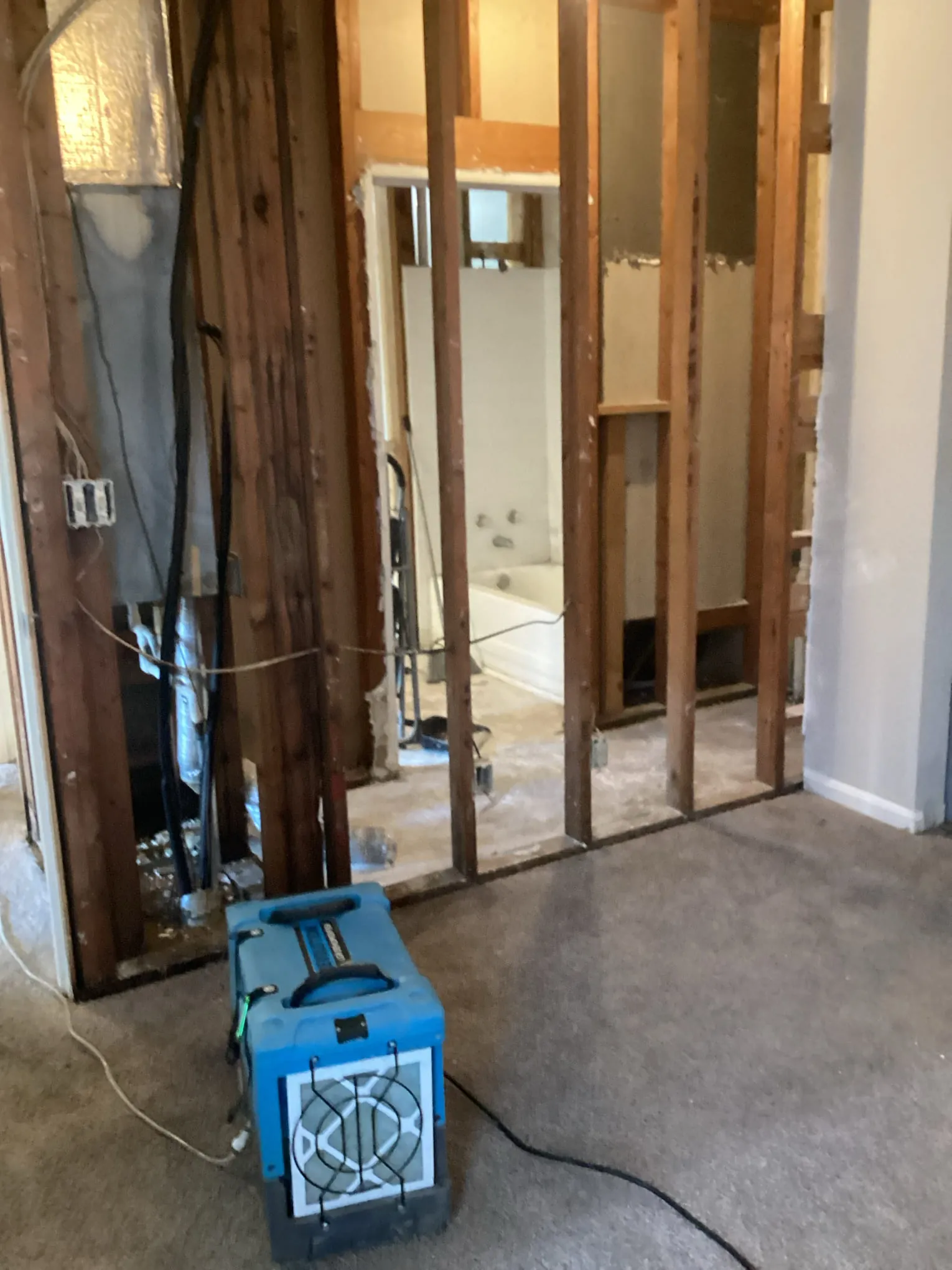 Commercial air filtration unit running against an opened wall cavity during odor treatment